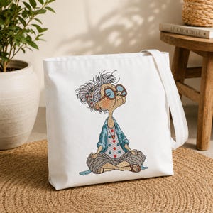 White tote bag featuring a Meditating Grandma machine embroidery design with a funny zen yoga granny, showing the finished embroidery on a reusable shopping bag for everyday use