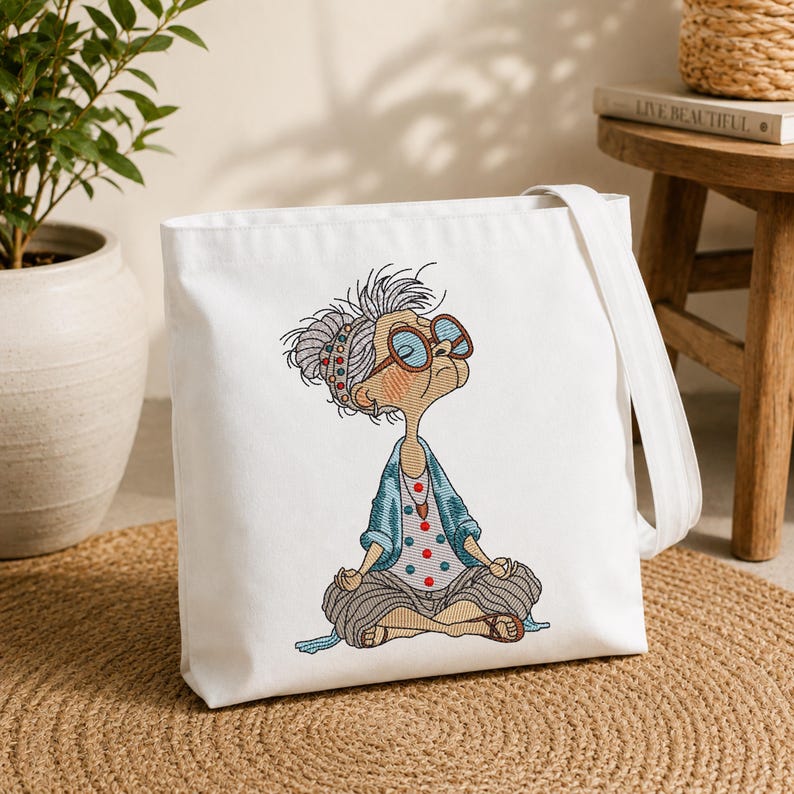 White tote bag featuring a Meditating Grandma machine embroidery design with a funny zen yoga granny, showing the finished embroidery on a reusable shopping bag for everyday use
