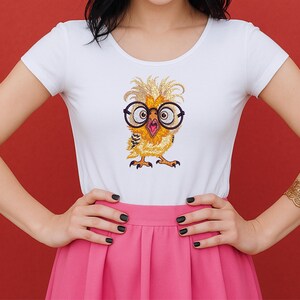 Woman wearing white fitted t-shirt with adorable baby owl embroidery design featuring oversized glasses, shown on red background – ideal for American embroidery enthusiasts.
