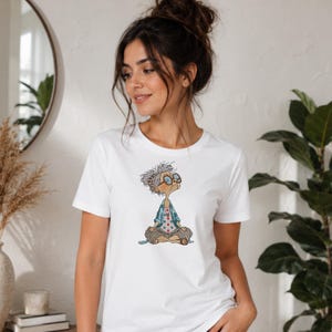 White T-shirt featuring a Meditating Grandma machine embroidery design with a funny zen yoga granny, showing the finished embroidery on casual apparel in a lifestyle mockup