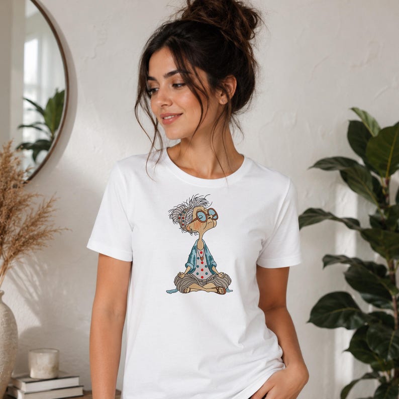 White T-shirt featuring a Meditating Grandma machine embroidery design with a funny zen yoga granny, showing the finished embroidery on casual apparel in a lifestyle mockup