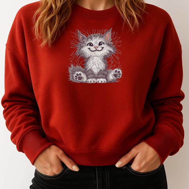 Close-up of woman wearing red sweatshirt with fluffy cat embroidery design, ideal for cozy gifts, pet lovers, and winter embroidery projects.