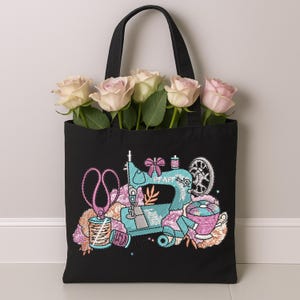 Black tote bag decorated with sewing machine embroidery design featuring scissors, thread, and sewing details – digital download embroidery file for personalizing bags, DIY crafts, and handmade sewing projects