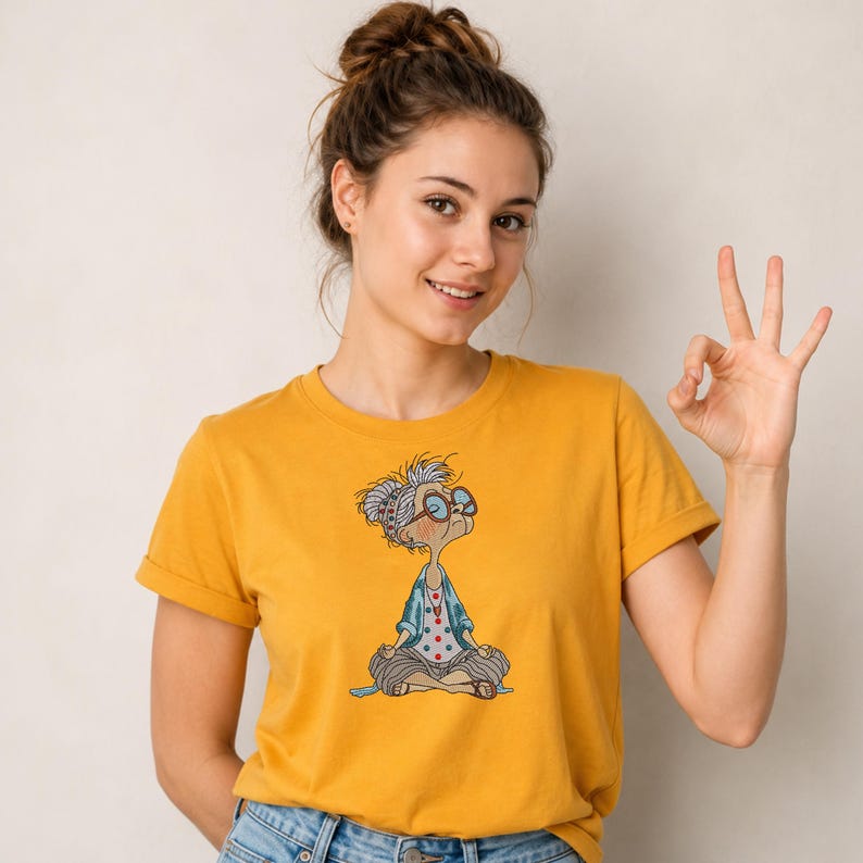 Yellow T-shirt featuring a Meditating Grandma machine embroidery design with a funny yoga granny in a lotus pose, showing how the embroidery looks on apparel