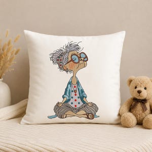 White decorative pillow featuring a Meditating Grandma machine embroidery design with a funny zen yoga granny, showing the finished embroidery for home décor and cushion projects