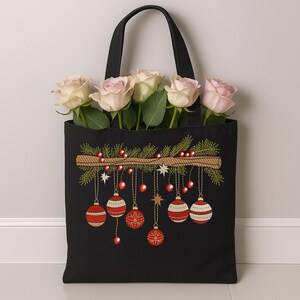 Christmas ornament embroidery on black tote bag with red baubles and pine branch – festive holiday design used for gift or décor