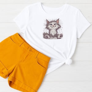 Flat lay of white t-shirt with cute cat embroidery design and mustard yellow shorts, perfect for baby gifts, kids fashion, and embroidery lovers.