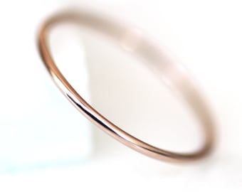 May include: A simple, thin, rose gold bangle bracelet. The bracelet is smooth and polished.