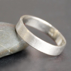 May include: A simple silver band ring with a brushed finish.