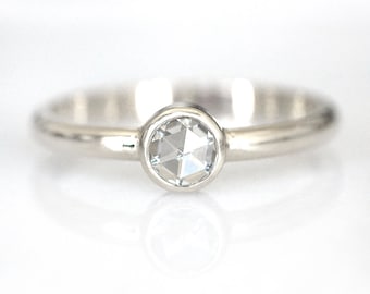 May include: A silver ring with a clear, round, faceted gemstone.