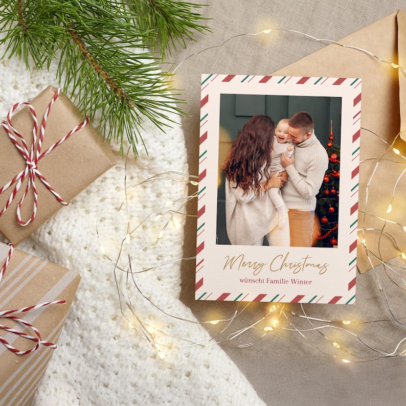 May include: A Christmas card with a family photo, framed with red and green diagonal stripes. The card reads "Merry Christmas" in gold script, with gifts wrapped in brown paper and string.