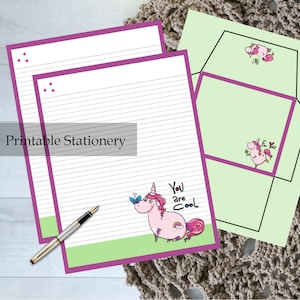 May include: Printable stationery set with a pink unicorn design. The stationery includes two sheets of lined paper with a purple border and a matching envelope. The unicorn is holding a butterfly and has the text "You are Cool" above it.