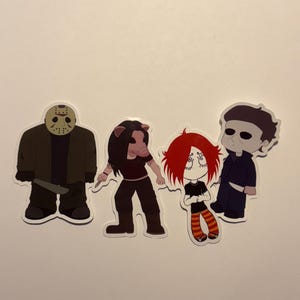 May include: Four cartoon stickers featuring horror movie characters. Jason Voorhees in a hockey mask and holding a knife, a pig-masked character, a girl with red hair, and Michael Myers in a dark blue jumpsuit.