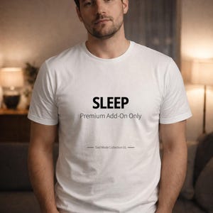 Puede incluir: Camiseta blanca con la palabra "SLEEP" impresa en negro, junto con "Premium Add-On Only" y "Dad Mode Collection 01". La camiseta es de manga corta y parece ser de algodón.