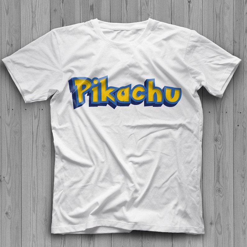 May include: White t-shirt with the word "Pikachu" in yellow and blue 3D lettering. The shirt is made of a soft material and has short sleeves and a crew neck.