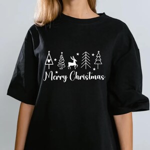 May include: Black t-shirt with a white Christmas design. The design includes a Christmas tree, a deer, stars, and the words "Merry Christmas" in a script font. The shirt has short sleeves.