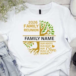 Op de afbeelding: Wit T-shirt met een familiebijeenkomst ontwerp. Het ontwerp bevat de tekst "2026 Family Reunion" boven een boomafbeelding. Onder de boom staat de tekst "Family Name" en de woorden "Our Roots Run Deep, Our Love Runs Deeper".