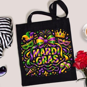May include: Black tote bag with a colorful Mardi Gras design. The design includes a bow, crown, mask, musical notes, and the words "Mardi Gras" in yellow, green, and purple.