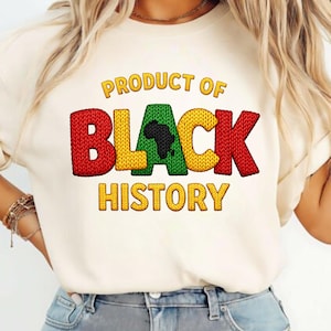 K&ouml;nnte beinhalten: Cremefarbenes T-Shirt mit dem Text "PRODUCT OF BLACK HISTORY" in Gelb, Rot und Gr&uuml;n. Das Wort "BLACK" zeigt eine schwarze Silhouette des afrikanischen Kontinents. Das Shirt hat einen Rundhalsausschnitt und kurze &Auml;rmel.