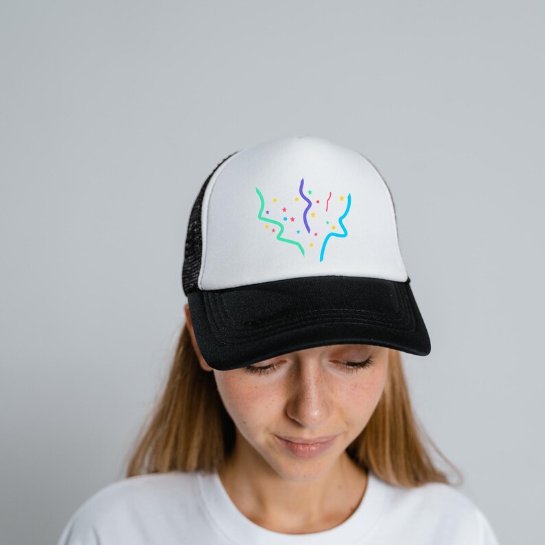 K&ouml;nnte beinhalten: Eine wei&szlig;e und schwarze Trucker-Kappe mit einem bunten Konfetti-Design. Die Kappe hat ein Netzr&uuml;cken und ein schwarzes Schild.