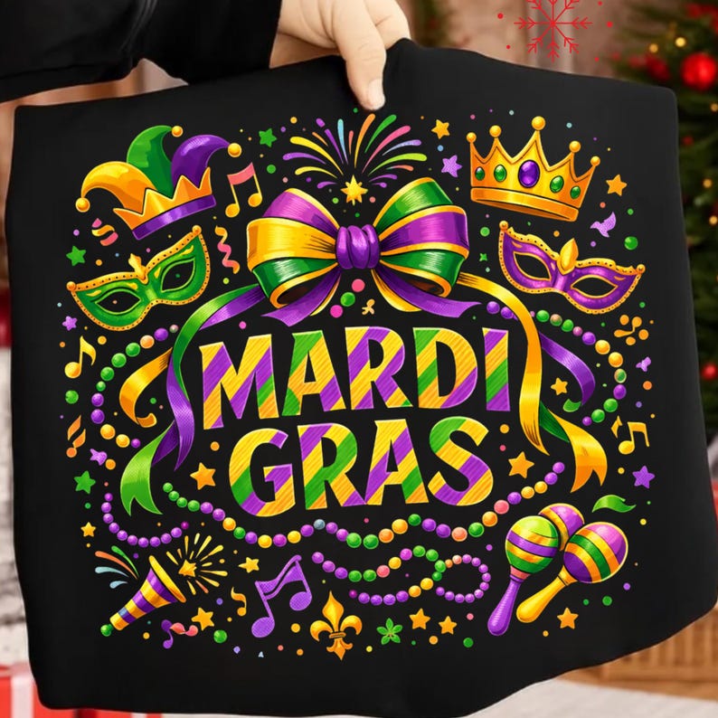May include: Black graphic tee with a vibrant Mardi Gras design. Features a large bow, crown, mask, and maracas in purple, green, and gold. The words "Mardi Gras" are prominently displayed in a festive font, surrounded by stars and musical notes.
