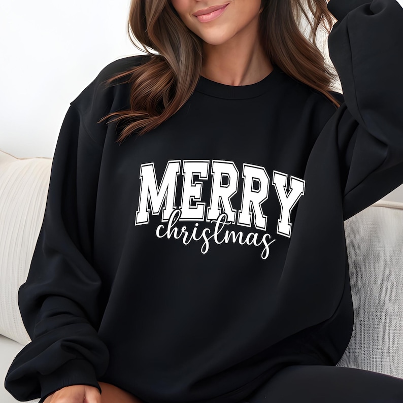 May include: Black sweatshirt with the words "MERRY christmas" in white block letters and script. The sweatshirt is a crew neck style and has long sleeves. The text is centered on the front of the shirt.