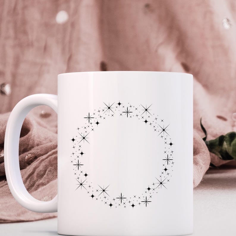 K&ouml;nnte beinhalten: Eine wei&szlig;e Keramiktasse mit einem schwarzen Sternenstrahl-Design um die Mitte. Die Tasse hat einen Henkel auf der linken Seite.