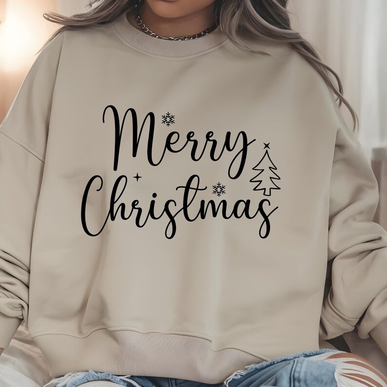 May include: Beige sweatshirt with the words "Merry Christmas" in black script. The design includes snowflakes and a Christmas tree. The sweatshirt has a crew neck and long sleeves.