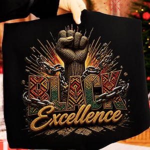 May include: Black t-shirt featuring a raised fist design with the words "BLACK Excellence". The design incorporates chains and a vibrant color palette of gold, green, red, and yellow.