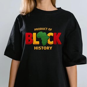K&ouml;nnte beinhalten: Schwarzes T-Shirt mit dem Text "PRODUCT OF BLACK HISTORY" in Rot, Gelb und Gr&uuml;n. Das Wort "BLACK" zeigt ein gr&uuml;nes Afrika-Design. Das Shirt hat kurze &Auml;rmel und eine lockere Passform.