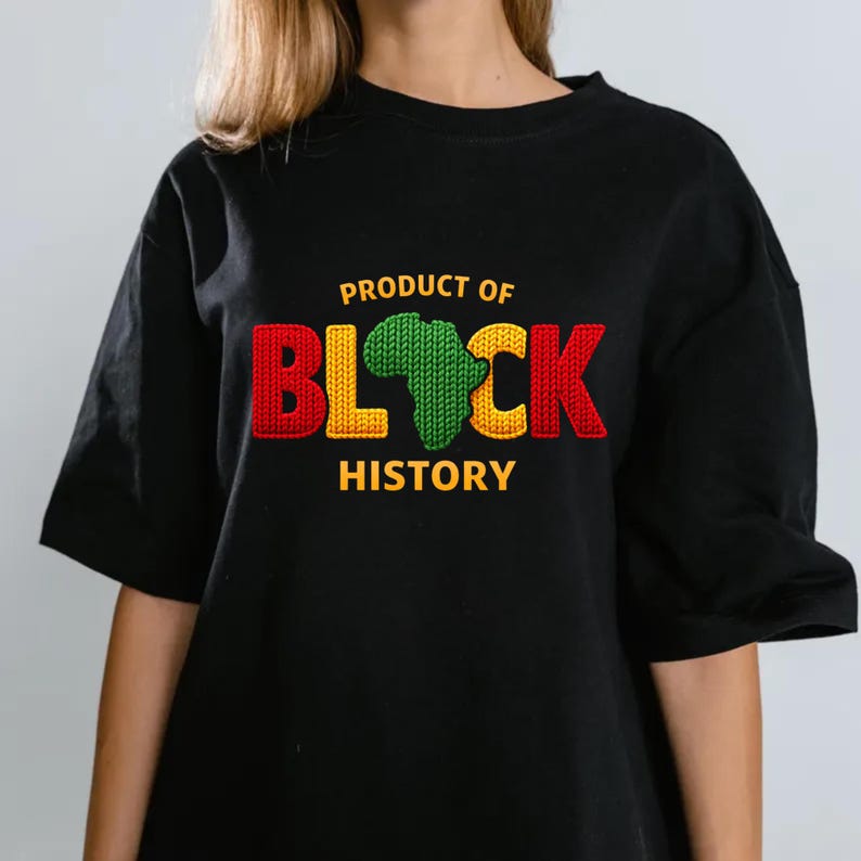 K&ouml;nnte beinhalten: Schwarzes T-Shirt mit dem Text "PRODUCT OF BLACK HISTORY" in Rot, Gelb und Gr&uuml;n. Das Wort "BLACK" zeigt ein gr&uuml;nes Afrika-Design. Das Shirt hat kurze &Auml;rmel und eine lockere Passform.