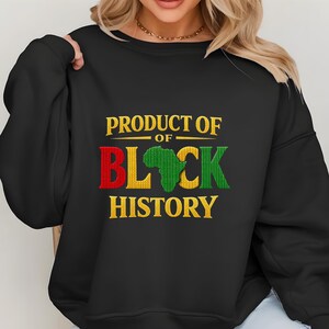 K&ouml;nnte beinhalten: Schwarzes Sweatshirt mit dem Text "PRODUCT OF BLACK HISTORY" in Gold, Rot, Gr&uuml;n und Gelb. Das Wort "BLACK" zeigt ein gr&uuml;nes Afrika-Kartendesign. Das Sweatshirt ist ein Rundhals-Stil.