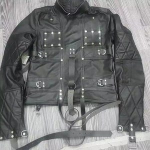 May include: Black leather jacket with multiple straps and buckles. The jacket has a quilted design on the sleeves and is adorned with silver studs.