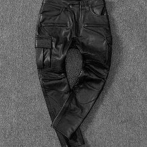 Puede incluir: Pantalón cargo de cuero negro con detalles de cremallera y múltiples bolsillos.