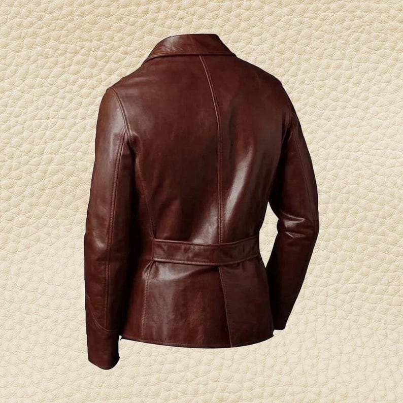 May include: A brown leather jacket with a notched collar and a belt at the waist. The jacket has long sleeves and a tailored fit. The leather appears to have a slight sheen, and the overall style is classic and sophisticated.
