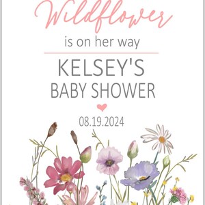 May include: A white card with a floral design and the text "a little Wildflower is on her way KELSEY'S BABY SHOWER 08.19.2024"