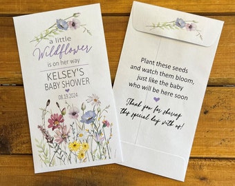 May include: A white card with a watercolor illustration of wildflowers and the text "a little Wildflower is on her way Kelsey's Baby Shower 08.19.2024". The back of the card has the text "Plant these seeds and watch them bloom, just like the baby who will be here soon. Thank you for sharing this special day with us!"