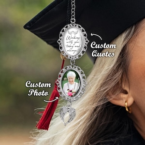 May include: A silver charm with a photo frame and a quote that says "Walking with you today and always!" The charm is attached to a red tassel and a pair of silver angel wings. The charm is a graduation gift for a loved one.