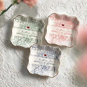 May include: Three square ceramic dishes with a gold trim, each featuring a map design in green, red, and blue. The text "Christian Joe, University of Michigan, Class of 2026" is printed on each dish, along with a graduation cap icon.