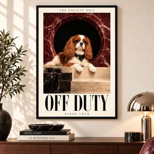 Könnte beinhalten: Ein gerahmtes Poster mit dem Titel THE SOCIETY EDIT zeigt einen braun-weißen Cavalier King Charles Spaniel mit schwarzem Halsband, der auf Steinstufen vor einem runden, roten Marmorbogen liegt, mit dem Text OFF DUTY STONE COLD.