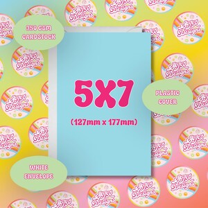 May include: A light blue card with the text "5X7" in pink. The card measures 127mm x 177mm and is made of 350 GSM cardstock. It includes a white envelope and a plastic cover.
