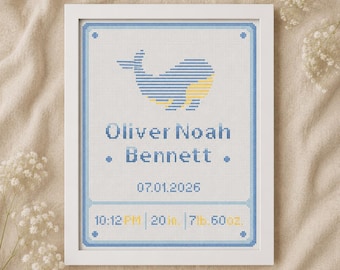 May include: A white framed cross-stitch birth announcement featuring a blue and yellow whale graphic. The text reads Oliver Noah Bennett, 07.01.2026, 10:12 PM, 20 in., and 7 lb. 6 oz. The design includes a blue border with small diamond accents.