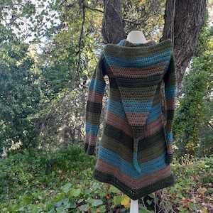 May include: A long, striped crocheted cardigan with a hood. The cardigan is made in shades of brown, green, and blue.