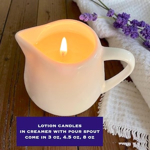 May include: A white ceramic creamer with a pour spout containing a lit candle. The text on the image reads: LOTION CANDLES IN CREAMER WITH POUR SPOUT COME IN 3 oz, 4.5 oz, 8 oz. The candle features a single glowing wick centred in the vessel.