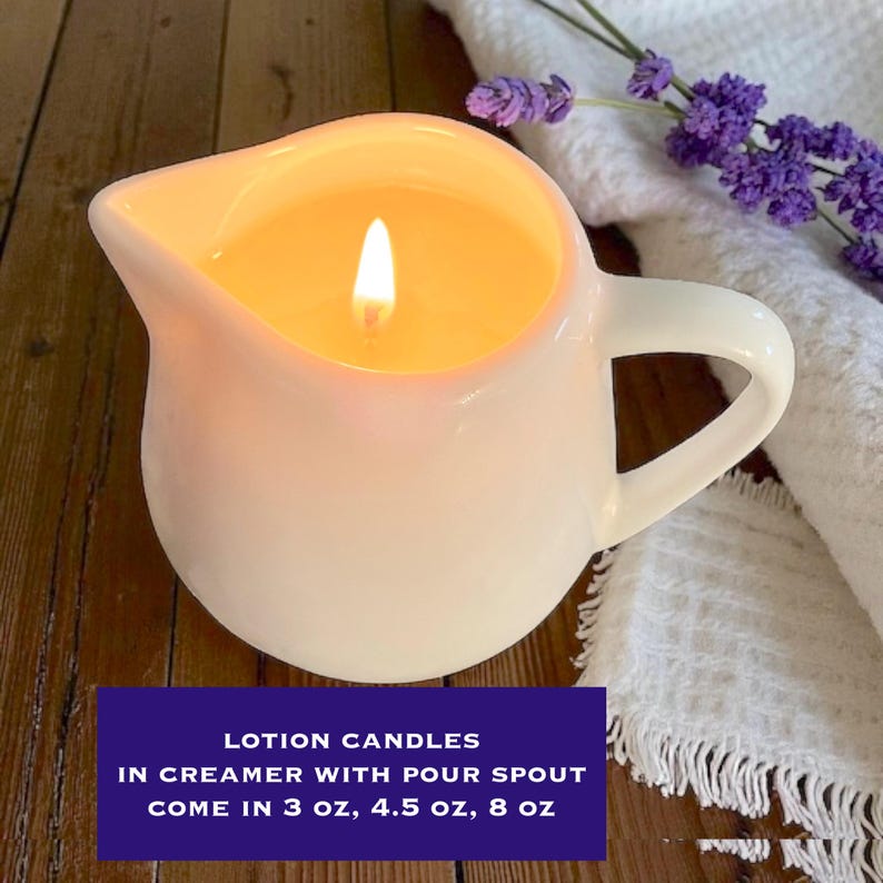 May include: A white ceramic creamer with a pour spout containing a lit candle. The text on the image reads: LOTION CANDLES IN CREAMER WITH POUR SPOUT COME IN 3 oz, 4.5 oz, 8 oz. The candle features a single glowing wick centred in the vessel.