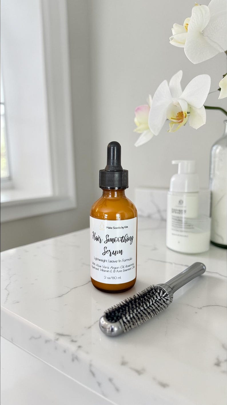 May include: An amber glass bottle with a black dropper cap containing Hair Smoothing Serum by Make Scents by Kim. The label lists a lightweight leave-in formula with Aloe Vera, Argan Oil, Rosemary, Vitamin E, and Pure Essential Oils, 2 oz.