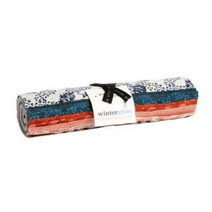 May include: A jelly roll of fabric strips featuring a variety of patterns in shades of white, dark blue, and orange. A white paper label is wrapped around the center, secured with a black ribbon, and displays the text winterglow collaborative collection.