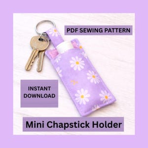 May include: A lavender chapstick holder with a daisy pattern, attached to a keyring with two keys. The text "PDF Sewing Pattern" and "Instant Download" are visible. The words "Mini Chapstick Holder" are also displayed.