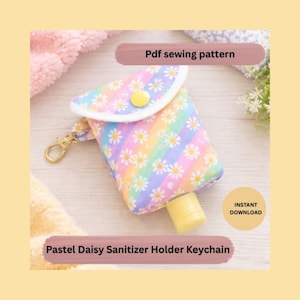 Könnte beinhalten: Ein pastellfarbener Desinfektionsmittelhalter-Schlüsselanhänger mit Gänseblümchen auf Regenbogenhintergrund. Der Halter hat einen gelben Knopfverschluss und einen goldfarbenen Verschluss. Der Text auf dem Bild lautet "Pdf sewing pattern" und "Instant Download".