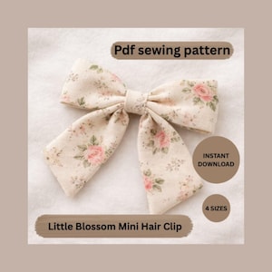 May include: A floral patterned hair clip in a bow shape. The clip features a cream-colored fabric with pink roses and green leaves. Text on the image reads "Pdf sewing pattern", "Instant download", "4 sizes", and "Little Blossom Mini Hair Clip".